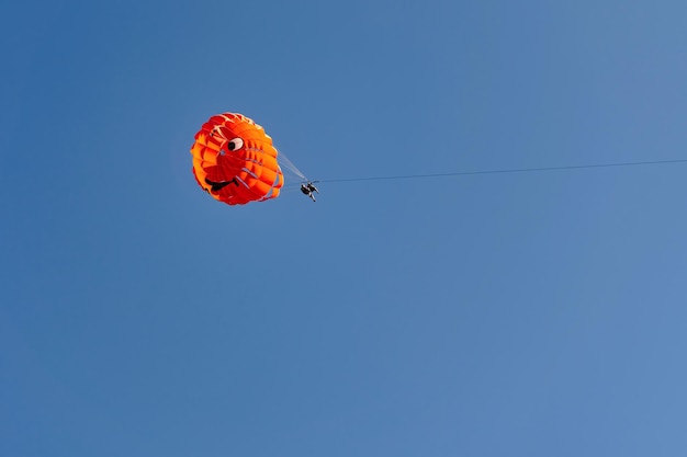 Parachute met vliegende man tegen blauwe hemelachtergrond