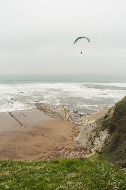 Paragliden over de groene kliffen op een bewolkte dag