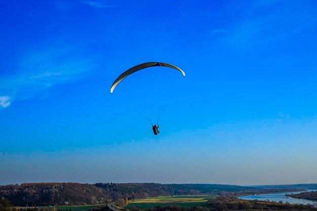 Paraglider die op de achtergrond van blauwe hemel vliegt