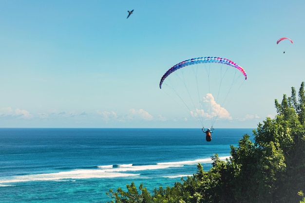 Paraglider flies in front of the blue ocean