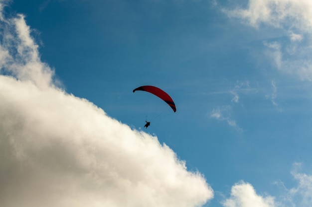 Paraglider flying over clouds in summer day