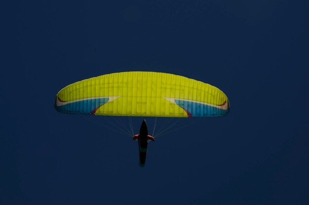 Фото Парапланер, виденный снизу с глубоким голубым небом на заднем плане