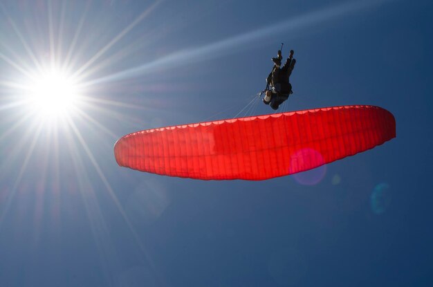 Paraglider taking off in deep blue sky flying high against the light