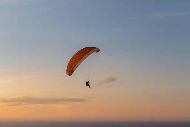 Paraglider vliegt over deze kust bij zonsondergang Paragliding sport concept