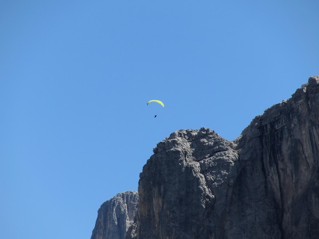 Paraglider with his yellow parachute flying near high italian mountains dolomites italy