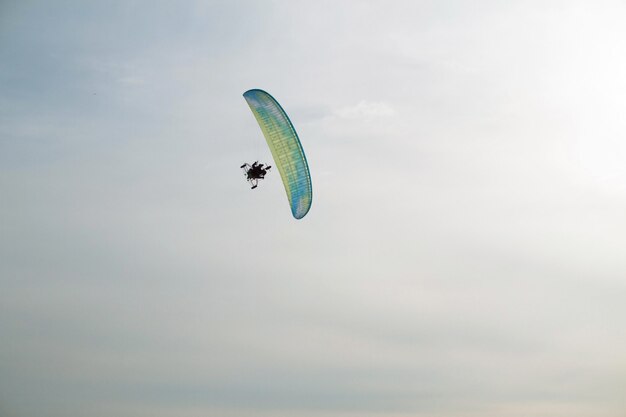 Paraglider with motor flies over the sea, which is covered with ice and snow