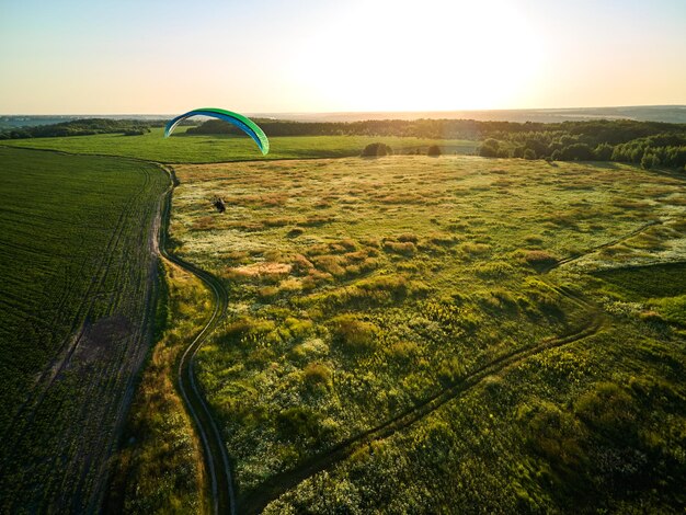 Paraglider zweeft hoog boven weelderige groene velden op een zonnige dag