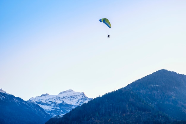 Paragliders flying with a paramotors with beautiful mountain view against blue sky