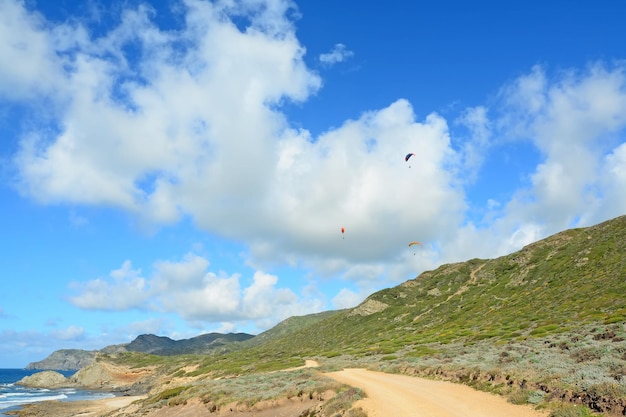 Paragliders vliegen over de kustlijn van Argentiera