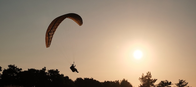 Paragliders vliegen tegen de achtergrond van een zonnige zonsondergang. Lucht sporten. Actieve rust buiten de stad.