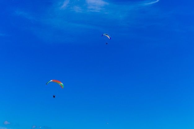 青い空でパラグライダー。パラグライダー付きパラシュートが飛んでいます。エクストリームスポーツ、自由の概念