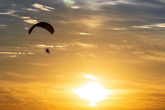 Paragliding silhouette with a beautiful background of the sky and the sun.