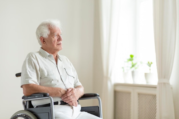 paralyzed elderly man in a wheelchair alone in a room
