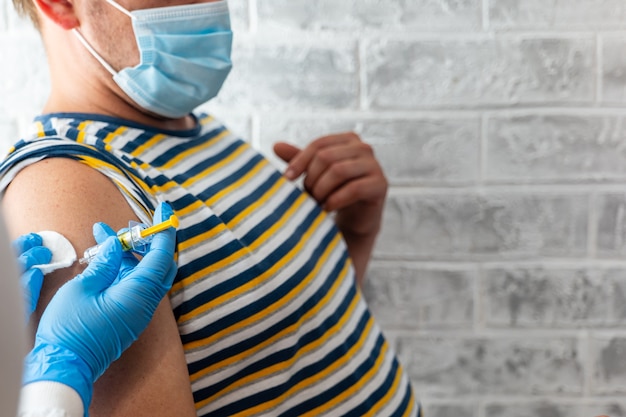 Photo paramedic make a man a coronavirus vaccine