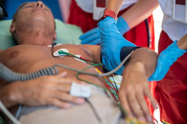 Paramedic wrapping the blood pressure cuff around the patient upper arm aided by her colleague