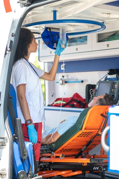 Foto professionista paramedico che prepara il paziente per una procedura di infusione endovenosa