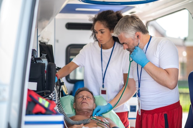 Photo paramedical staff examining the sick man in the ambulance vehicle