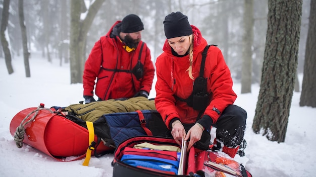 I paramedici del servizio di soccorso alpino forniscono operazioni all'aperto in inverno nella foresta, persona ferita in barella.