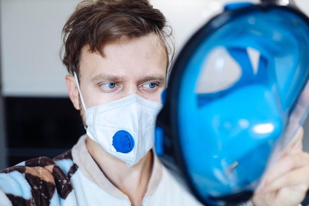 의료용 마스크를 쓴 편집증적인 남자는 바이러스로부터 보호하기 위해 스노클링 마스크를 쓴다