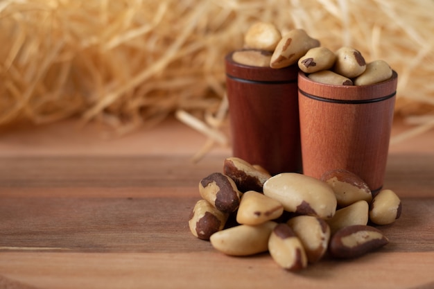 Foto paranoten op een houten tafel en in een houten kopjes met stro achtergrond. (castanha do brasil of castanha do para)