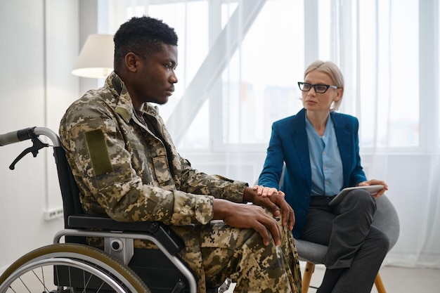 Paraplegic soldier in wheelchair talking with therapist