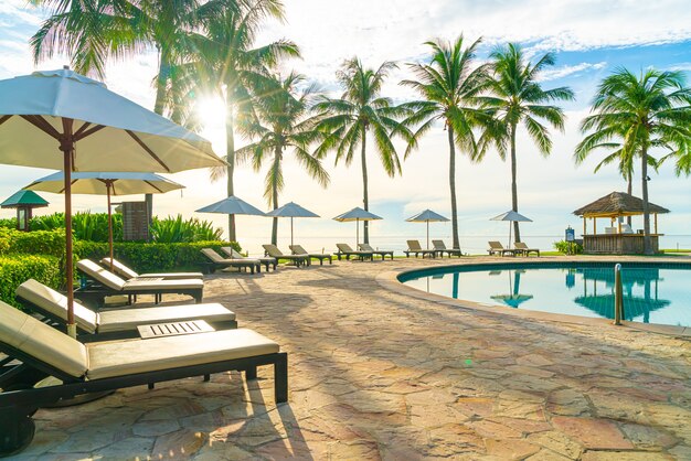 Paraplu en stoel rond zwembad in resorthotel voor vakantiereizen en vakantie in de buurt van zee oceaanstrand bij zonsondergang of zonsopgang