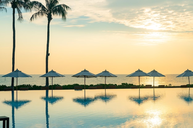 paraplu met bed zwembad rond zwembad met oceaan zee achtergrond bij zonsondergang of zonsopgang tijd - vakantie en vakantie concept