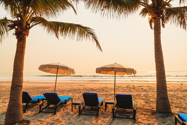 paraplu stoel strand met palmboom en zee strand bij zonsopgang - vakantie en vakantie concept