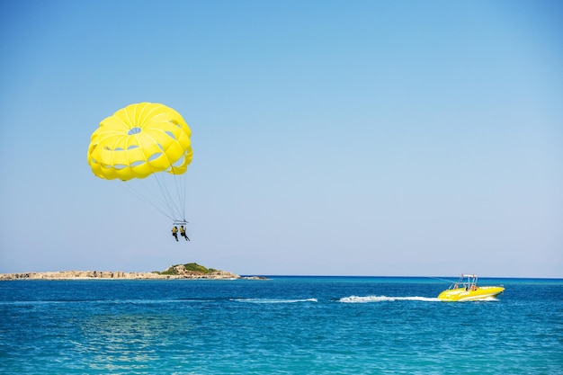 Parasailen boven de oceaan Gele parasailvleugel getrokken door een boot Sportactiviteit op het strand