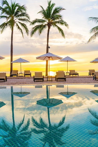 Parasol en stoel rond zwembad in hotelresort met zonsopgang in de ochtend - concept vakantie en vakantie