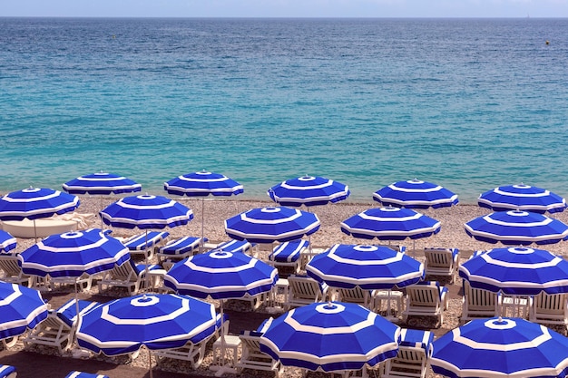 Parasols on beach of nice in sunny summer day with blue sky nice french riviera france