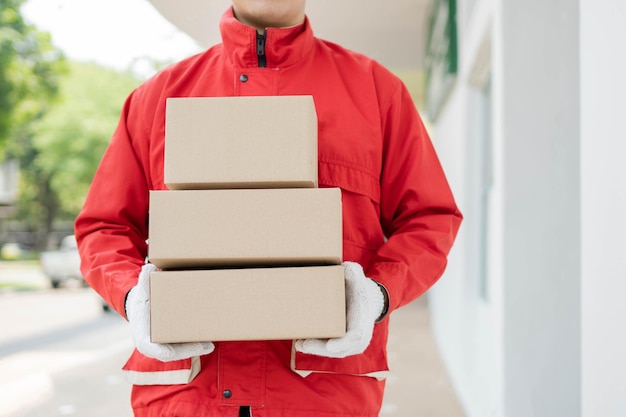 Photo parcel delivery concept the mailman standing holding three boxes of parcels
