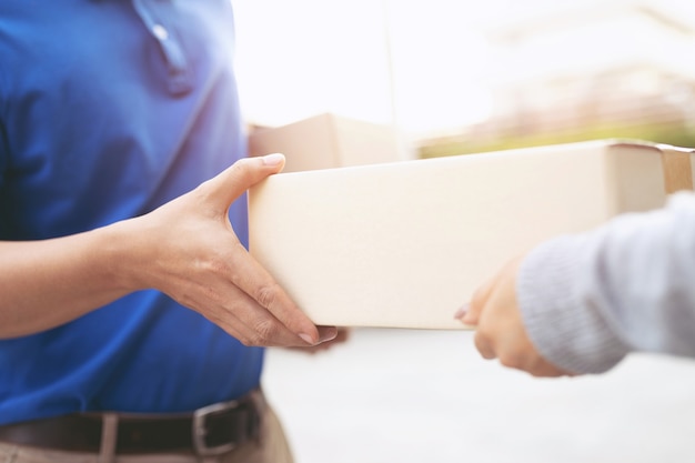 Foto addetto alla consegna pacchi di un pacco tramite un servizio di invio a domicilio. consegna a mano cliente di presentazione che accetta una consegna di scatole dal fattorino.