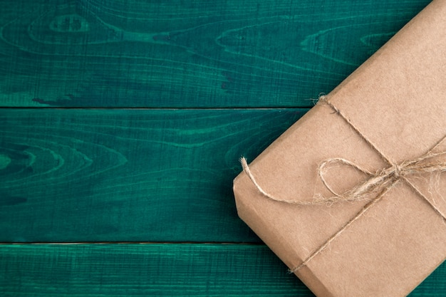 Посылка, подарочная упаковка в экологически чистой бумаге на темно-зеленом фоне деревянные. вид сверху