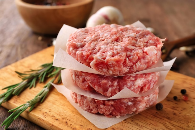 Parchment paper with fresh minced meat on wooden board