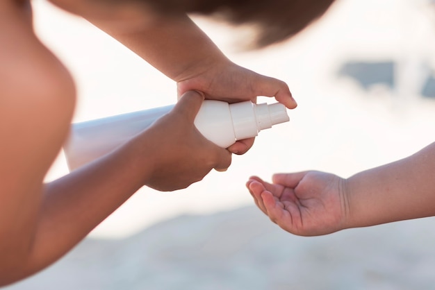 Genitore che applica la crema solare nella mano del bambino