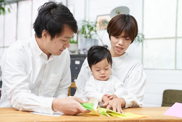 Parent and child playing origami indoors