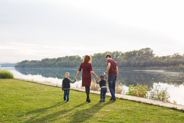 親、子供、自然の概念-水辺で2人の息子と遊ぶ家族