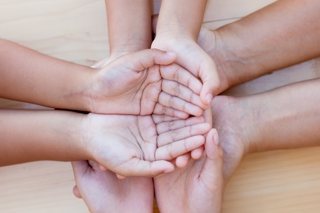 Genitore e bambini che si tengono per mano insieme su fondo di legno