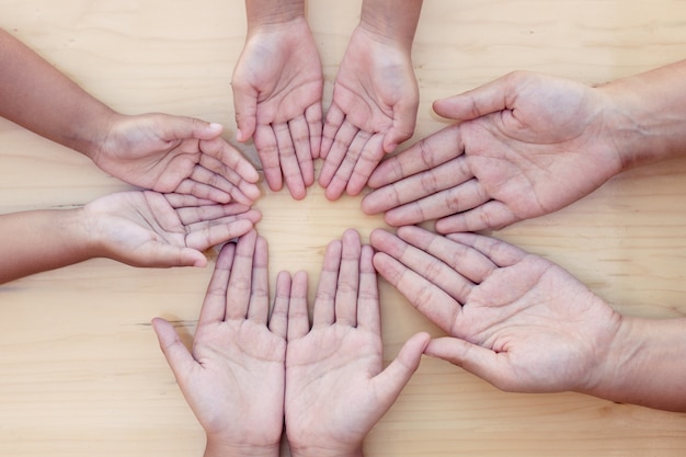 Foto genitori e figli aprono il palmo della mano in cerchio mostrando unità e lavoro di squadra