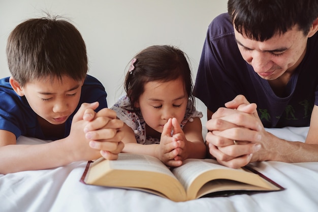 親と子供たちはベッドで祈り、家族は一緒に祈る