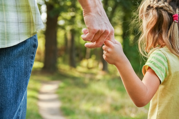 幸せな表面で子供の手を握っている親