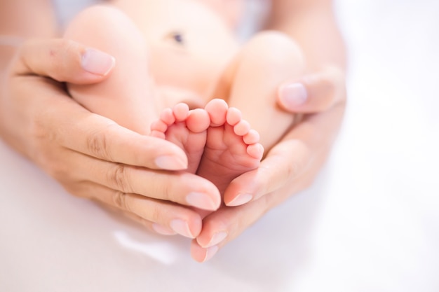 Parent holding in the feet of newborn baby.