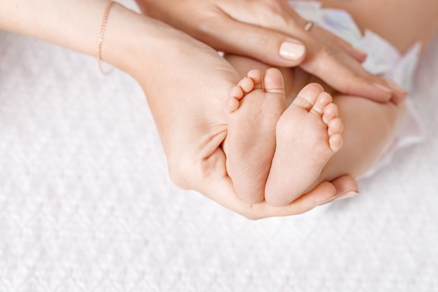 写真 生まれたばかりの赤ちゃんの足を手で保持している親。手のクローズアップに小さな新生児の足。
