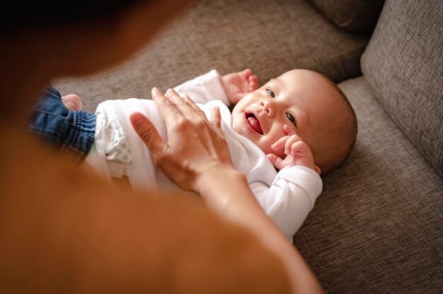 親は休日に自宅で幼児の腕の赤ちゃんの息子と遊ぶ。家族、父、息子、赤ちゃん、幸せ、ライフスタイルのコンセプト。