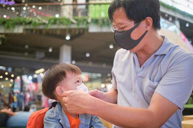 Parent putting mask on his Asian toddler boy child