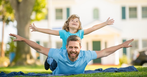 親は夏の日の子育てで子供と一緒に草のお父さんの小さな子供男の子とリラックス