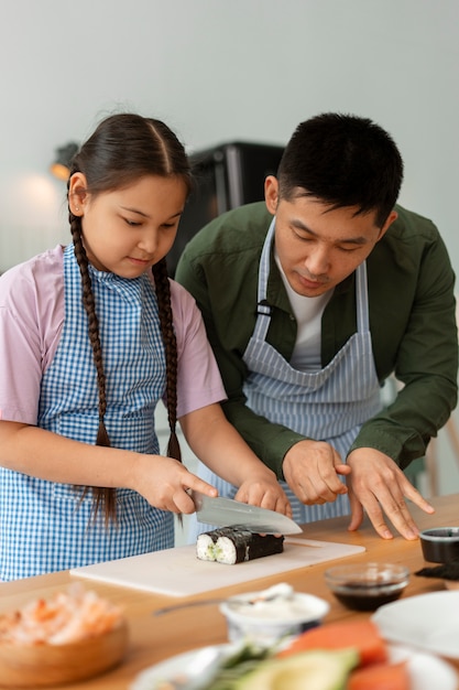 Photo parent teaching kid how to make sushi
