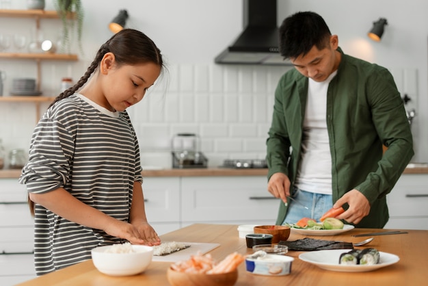 子どもに寿司を作る方法を教える親