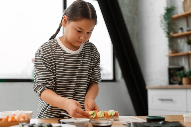 Photo parent teaching kid how to make sushi